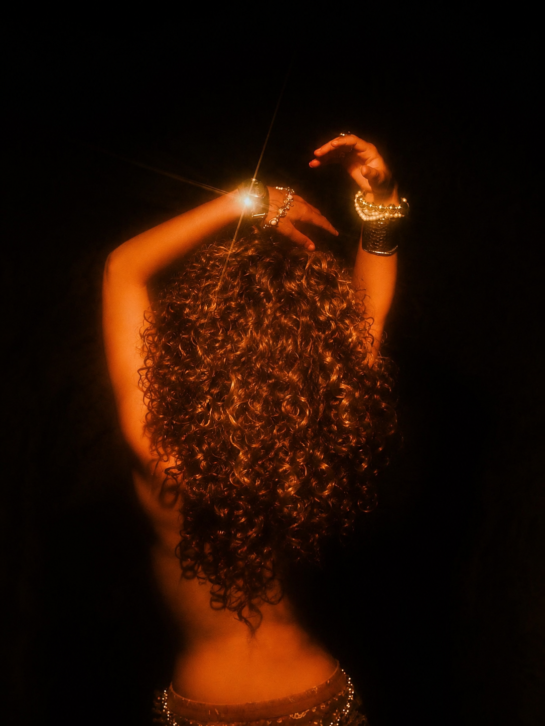 Woman with voluminous curly hair illuminated against dark background